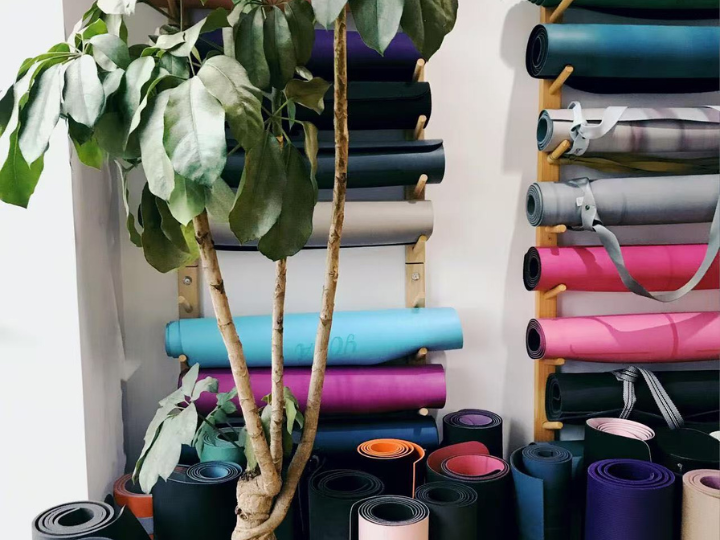A collection of high-quality PU yoga mats in various colors, neatly stored on wooden racks, showcasing Wellfitsource's customizable and durable yoga mat options.