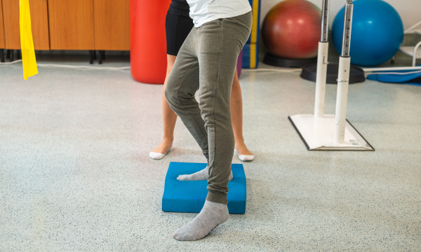 Person using a TPE balance pad for balance training in a rehabilitation setting.