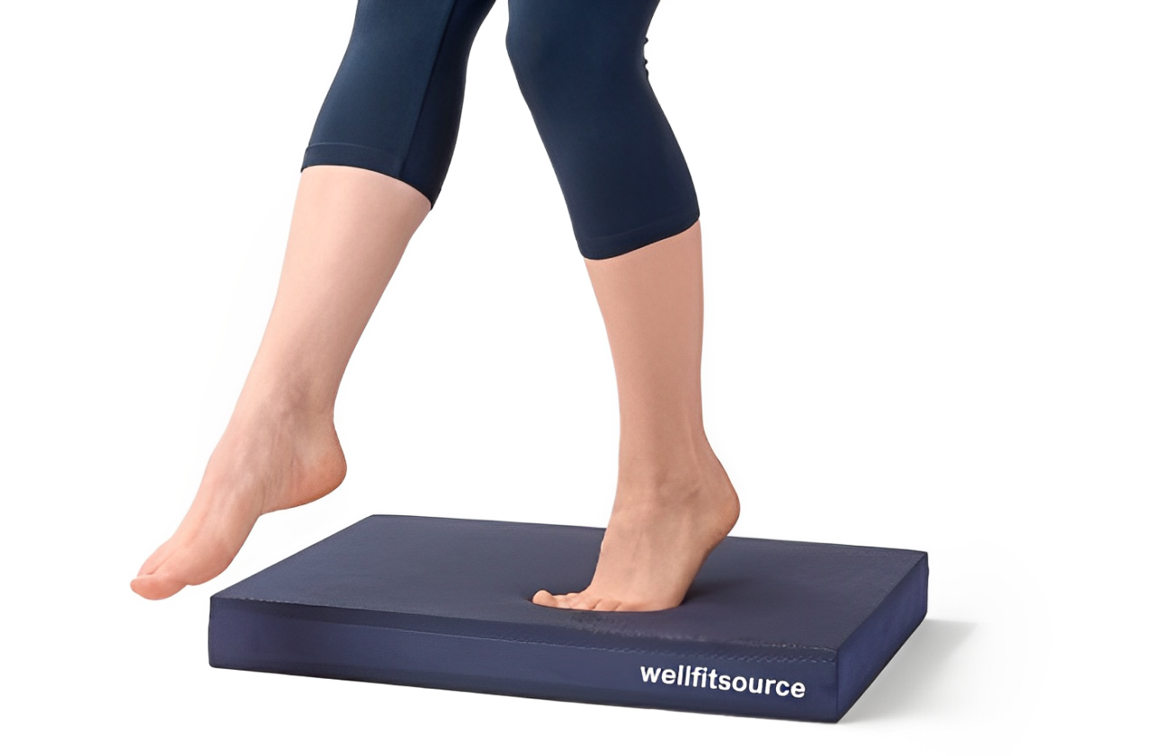 Close-up of woman balancing barefoot on a dark blue Wellfitsource balance pad.
