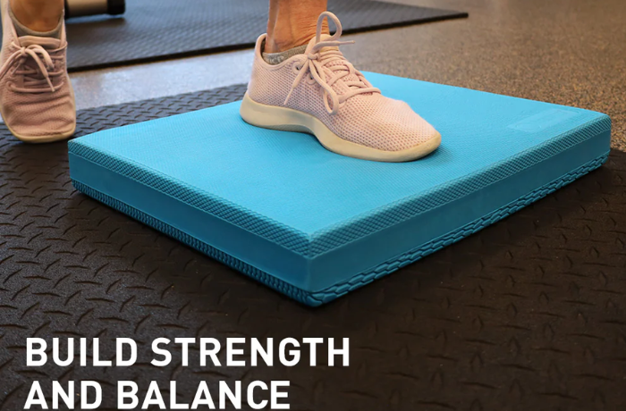 Fuß auf einem blauen Balance Pad beim Training auf schwarzem Gummiboden