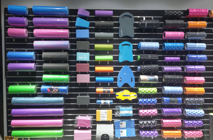 Wall-mounted display of assorted foam rollers and fitness accessories in various colors and textures.