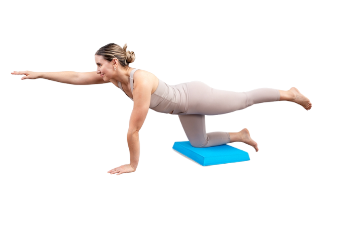 Woman performing bird-dog exercise on a blue foam balance pad.