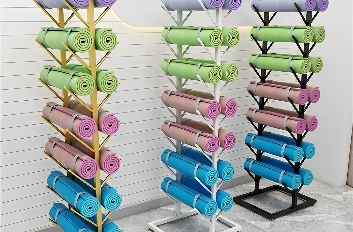 Colorful yoga mats stacked on gold, white, and black vertical storage racks