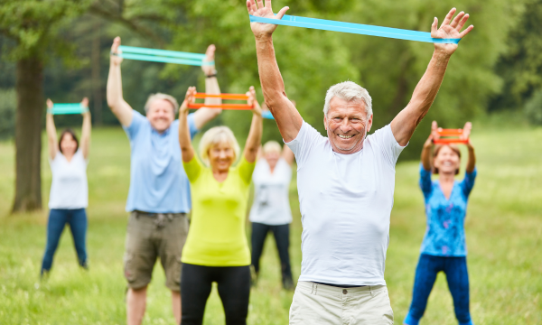 Seniors exercising outdoors with resistance bands in a group fitness session