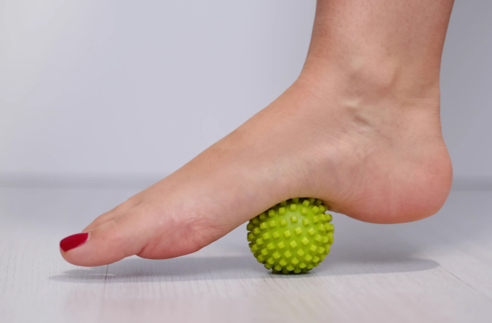 Foot pressing on green spiky massage ball
