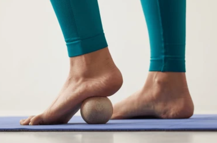 Woman using wooden ball foot massager for arch relief
